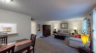 This single-floor residence features two bedrooms and two full bathrooms within a thoughtfully designed layout. The open living area is carpeted and bathed in natural light from large windows dressed with sheer curtains and blinds, creating a bright and welcoming atmosphere. A dedicated dining area adjacent to the living room provides a defined space for meals, complete with a pass-through window connecting to the kitchen.

The galley-style kitchen is outfitted with white cabinetry, light granite-style countertops, a double basin sink, and full suite of white appliances, all set atop wood-look vinyl flooring that extends throughout the wet areas of the home.

The primary bedroom is spacious and carpeted, featuring a ceiling fan with light fixture and access to natural light through a large window. The second bedroom is equally well-proportioned with soft carpet and neutral wall tones. Both bathrooms mirror each other in design, offering white vanity cabinetry, light countertops, a tub-shower combination, and durable wood-look vinyl flooring. Textured ceilings are consistent throughout the home, adding a classic residential character.
