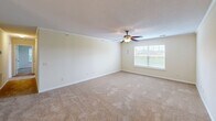 Located at 2815 Kinloch Ct in Florence, South Carolina, this single-floor, 2-bedroom, 2-bathroom home offers a practical and comfortable layout with consistent neutral finishes throughout. The kitchen is well-appointed with warm honey-toned wood cabinetry, dark countertops, a double-basin sink, white appliances including a range, microwave, and refrigerator, and light tile flooring. It opens into a dining area illuminated by a classic chandelier, creating a welcoming flow between the two spaces. The generously sized primary bedroom features plush carpeting, a ceiling fan with light fixture, and multiple windows that invite natural light and outdoor views. It is complemented by a dedicated walk-in closet with built-in wire shelving for ample storage. The second bedroom is similarly finished with carpet flooring, a ceiling fan, and a window with pleasant exterior views. Both bathrooms are functionally designed, each featuring a tub-shower combination, toilet, vanity with warm wood cabinetry, and hardwood-style flooring. Additional utility space and a textured ceiling throughout add to the home's practical character. Crown molding and consistent neutral wall tones provide a clean, move-in-ready aesthetic across the entire residence.