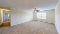 Located at 2815 Kinloch Ct in Florence, South Carolina, this single-floor, 2-bedroom, 2-bathroom home offers a practical and comfortable layout with consistent neutral finishes throughout. The kitchen is well-appointed with warm honey-toned wood cabinetry, dark countertops, a double-basin sink, white appliances including a range, microwave, and refrigerator, and light tile flooring. It opens into a dining area illuminated by a classic chandelier, creating a welcoming flow between the two spaces. The generously sized primary bedroom features plush carpeting, a ceiling fan with light fixture, and multiple windows that invite natural light and outdoor views. It is complemented by a dedicated walk-in closet with built-in wire shelving for ample storage. The second bedroom is similarly finished with carpet flooring, a ceiling fan, and a window with pleasant exterior views. Both bathrooms are functionally designed, each featuring a tub-shower combination, toilet, vanity with warm wood cabinetry, and hardwood-style flooring. Additional utility space and a textured ceiling throughout add to the home's practical character. Crown molding and consistent neutral wall tones provide a clean, move-in-ready aesthetic across the entire residence.