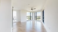 This thoughtfully designed single-floor residence offers three bedrooms, two bathrooms, and a generous overall footprint. The open-concept layout connects the living, dining, and kitchen areas seamlessly, with light wood-tone flooring flowing throughout the main spaces. The living room is a standout, featuring dramatic floor-to-ceiling corner windows with black metal frames that flood the space with natural light and offer sweeping panoramic views of the surrounding cityscape. A ceiling fan adds comfort to this expansive area.

The kitchen features warm, natural wood cabinetry with matte black hardware paired with clean white countertops, creating a modern yet inviting aesthetic. A sliding barn door accent adds architectural character. A light-filled hallway connects the main living area to the private bedrooms.

The three bedrooms are carpeted for comfort and include ceiling fans and window blinds for light control. The generously sized primary bedroom includes a well-appointed en-suite bathroom featuring a dual-sink vanity with warm wood cabinetry, a backlit mirror, tile flooring, and matte black fixtures. A soaking tub with tiled surround completes the second bathroom. Three closets, including walk-in storage with dual hanging rods, provide ample organization throughout the residence.