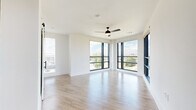 This thoughtfully designed single-floor residence offers three bedrooms, two bathrooms, and a generous overall footprint. The open-concept layout connects the living, dining, and kitchen areas seamlessly, with light wood-tone flooring flowing throughout the main spaces. The living room is a standout, featuring dramatic floor-to-ceiling corner windows with black metal frames that flood the space with natural light and offer sweeping panoramic views of the surrounding cityscape. A ceiling fan adds comfort to this expansive area.

The kitchen features warm, natural wood cabinetry with matte black hardware paired with clean white countertops, creating a modern yet inviting aesthetic. A sliding barn door accent adds architectural character. A light-filled hallway connects the main living area to the private bedrooms.

The three bedrooms are carpeted for comfort and include ceiling fans and window blinds for light control. The generously sized primary bedroom includes a well-appointed en-suite bathroom featuring a dual-sink vanity with warm wood cabinetry, a backlit mirror, tile flooring, and matte black fixtures. A soaking tub with tiled surround completes the second bathroom. Three closets, including walk-in storage with dual hanging rods, provide ample organization throughout the residence.