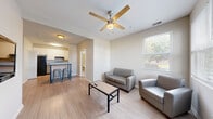 Located at 7 Traders Cir in Normal, IL, this single-floor, 2-bedroom, 2-bathroom unit offers a practical and well-organized layout. The living room is a bright, welcoming space featuring light wood-style flooring, a ceiling fan, and multiple windows that allow natural light to fill the room. The open sightlines from the living area connect seamlessly to the kitchen, which is equipped with white shaker-style cabinetry, a black refrigerator, an electric range, a dishwasher, and a blue-toned countertop — providing both function and a clean, modern aesthetic. A louvered utility closet in the kitchen adds convenient in-unit storage. Both bedrooms are carpeted and comfortably sized, with the primary bedroom featuring a ceiling fan and natural light from a window with outdoor views. The second bedroom also benefits from a window with natural light. Each bedroom is paired with its own bathroom, both of which feature wood-style flooring and a walk-in shower with a framed glass door. The neutral, light color palette used throughout the unit creates a cohesive and airy atmosphere, making the space feel open and easy to personalize.