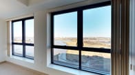 Unit 913 is a thoughtfully designed 1-bedroom, 1-bathroom residence situated on the ninth floor, offering a single-level layout that maximizes both comfort and functionality. The unit's most striking feature is its expansive floor-to-ceiling windows framed in sleek black casings, which frame breathtaking panoramic views of a natural wetlands landscape, open water, and distant cityscape. Natural light floods the interior throughout the day, creating a bright and airy atmosphere that complements the clean, modern aesthetic. The interiors showcase a contemporary design sensibility, with crisp white walls and a neutral color palette that allows the outdoor scenery to take center stage. The open layout connects living areas seamlessly, enhancing the overall sense of space. The bedroom and bathroom are well-appointed, maintaining the same refined, modern character found throughout the unit. The elevated position of this residence ensures unobstructed sightlines across the natural surroundings, offering a rare connection to the outdoors from within a modern residential setting. Whether enjoying the golden light of sunrise or the quiet stillness of the wetlands, the views from Unit 913 provide a truly distinctive living experience.