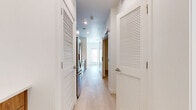 This well-designed one-bedroom, one-bathroom unit in Overland Park, KS offers a thoughtfully organized layout with modern finishes throughout. The open kitchen and living area serves as the heart of the space, featuring a galley-style kitchen equipped with stainless steel appliances — including a French door refrigerator, electric range, and over-the-range microwave — paired with warm wood lower cabinetry, sleek upper cabinets, white quartz countertops, a subway tile backsplash, and a stainless steel undermount sink. Light hardwood flooring runs throughout the main living areas and hallway, lending a clean, airy feel to the space. The hallway is lined with louvered bi-fold doors providing access to a closet and laundry area, keeping the layout organized and functional. The living room offers natural light through large windows fitted with blinds, while a door provides additional access. The bedroom is carpeted for comfort and benefits from natural light. The bathroom is finished with large-format light tile flooring, a wood-toned vanity with a white countertop, and a full tub-shower combination with a white tile surround. Clean white walls and recessed lighting throughout contribute to the unit's bright, contemporary ambiance.