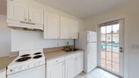 Located at 345 30th St in West Palm Beach, Florida, this single-floor unit offers a practical and well-organized layout designed for comfortable living. The open-concept living and dining area is a standout feature, showcasing warm hardwood flooring that runs throughout, bright white walls, and multiple windows that invite generous natural light from multiple directions. The space feels airy and open, with a smooth flow between the living area and the adjoining kitchen.

The kitchen is efficiently designed with white cabinetry, a neutral-toned countertop, an electric range, and a full-size refrigerator. A single-basin sink with a classic faucet is positioned beneath upper cabinets for added storage. A glass-panel door in the kitchen provides direct access to an outdoor patio area overlooking a community pool, offering pleasant views and easy outdoor access.

The transition between the kitchen and the main living area is defined by a half-wall peninsula, which subtly separates the spaces while maintaining an open feel. White tile flooring in the kitchen and bathroom contrasts neatly with the hardwood in the living areas.

The bathroom is clean and simply finished, featuring white wall tile, a pedestal sink with chrome fixtures, a wall mirror, and a window that allows natural light to brighten the space. Overall, this unit presents a tidy, functional living environment in a sunny West Palm Beach setting.
