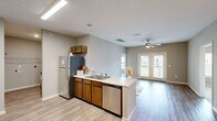 Located on Tranquility Drive in Rossville, Georgia, this single-floor residence offers a well-designed, open layout that promotes a comfortable and functional living experience. The kitchen is a standout feature, equipped with stainless steel appliances including a refrigerator, electric range with microwave, and dishwasher. Warm-toned wood cabinetry pairs with light countertops, while wood-look luxury vinyl plank flooring flows throughout the main living areas, creating a cohesive and modern aesthetic. The kitchen opens seamlessly into the living area, which is accented by a ceiling fan and a set of French doors that invite natural light and provide outdoor access. The bedrooms are carpeted for added comfort, each featuring ceiling fans and windows that bring in natural light. The primary bedroom offers generous proportions with a view of the surrounding community. Two full bathrooms serve the residence, each featuring a tub-shower combination, wood-toned vanity cabinetry, and light countertops. The second bathroom is notably spacious, with wood-look flooring and ample wall space. A dedicated laundry area with shelving is conveniently accessible from the kitchen corridor. Neutral wall tones throughout the home create a clean, versatile backdrop suitable for a variety of interior styles.