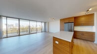 Situated along the scenic Lake Merritt Path in Oakland, CA, this contemporary residence offers a thoughtfully designed single-floor layout that blends modern aesthetics with functional living. The open-concept living and dining area is anchored by expansive floor-to-ceiling sliding glass doors that flood the space with natural light and provide direct access to a private balcony overlooking Lake Merritt and the Oakland city skyline — a truly striking backdrop for everyday living.

Light hardwood flooring flows seamlessly throughout the main living areas, complementing the clean white walls and creating a bright, airy atmosphere. The kitchen is a standout feature, outfitted with warm wood-grain cabinetry, white quartz countertops, a central island, a white subway tile backsplash, and a full suite of stainless steel appliances including a refrigerator, range, microwave, and dishwasher.

The bathrooms continue the cohesive design language, featuring warm wood vanities with white quartz countertops, large mirrors, and neutral tile flooring. One bathroom includes a soaking tub, while another offers a clean, minimalist vanity layout. The entry foyer connects directly to the kitchen, providing a practical and welcoming transition into the home. Overall, the space exudes a polished, contemporary character with an emphasis on natural light and panoramic views.