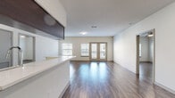 This single-floor residence offers a thoughtfully designed layout that balances open living spaces with comfortable private areas. The main living area is anchored by rich, dark hardwood-style flooring that runs throughout the unit, complementing the neutral, light-toned walls. A kitchen peninsula transitions seamlessly into the open living space, which features dark espresso cabinetry, sleek white countertops, stainless steel appliances—including a range, microwave, and dishwasher—and track lighting overhead. The living room receives generous natural light through multiple windows and a set of French doors that open onto a private balcony, creating an airy and inviting atmosphere. The bedrooms are well-proportioned, each featuring ceiling fans, large windows, and the same warm hardwood-style flooring. A spacious walk-in closet with wire shelving provides ample storage. The unit includes two bathrooms: one featuring a vanity with bold blue cabinetry, a white countertop, a large mirror, and a tub-shower combination with white tile surround; the second bathroom also offers a full tub-shower with matching white tile. Throughout, the design maintains a clean, contemporary aesthetic with consistent finishes and a bright, open feel.