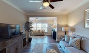 This thoughtfully designed single-floor residence offers a seamless blend of comfort and style across its well-proportioned living spaces. The expansive living area is highlighted by rich hardwood flooring, crown molding, and ceiling fans, flowing naturally into a bright sunroom-style sitting area framed by large windows that invite abundant natural light and outdoor views. A dedicated dining room features classic wainscoting, crown molding, and an elegant chandelier, creating a refined setting for gatherings. The kitchen is outfitted with crisp white shaker-style cabinetry, dark granite countertops, and a full suite of stainless steel appliances, offering both functionality and visual appeal. The bedrooms are generously sized, with plush carpeting, ceiling fans, and windows that provide natural light and outdoor views. Each bathroom is finished with granite-topped white vanities and tub-shower combinations — one with tile flooring and another with hardwood — both offering clean, functional design. Throughout the residence, a warm neutral color palette, consistent trim work, and quality finishes create a cohesive and inviting ambiance suited for comfortable everyday living.