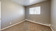Located at 2634 E Yampa St in Colorado Springs, CO, this one-bedroom, one-bathroom unit offers a compact and efficiently designed single-floor layout. The space is finished with neutral gray walls and white trim throughout, creating a clean and consistent aesthetic. Carpet flooring runs through the hallway, living room, and bedroom, while the kitchen features light wood-tone vinyl plank flooring. The kitchen is equipped with white cabinetry, a tile countertop, a double-basin sink, and white appliances including a range and refrigerator, all illuminated by a ceiling-mounted light fixture. A baseboard heating system is present throughout the unit. The bedroom is a comfortable size, featuring a window that allows natural light to filter in, carpeted flooring, and access to the hallway via a six-panel white door. Two closets provide convenient storage. The bathroom includes a full tub/shower combo unit with white surround. A carpeted hallway connects the rooms, with a window at the end adding additional natural light. The overall ambiance is straightforward and functional, suited for practical everyday living.