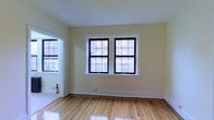 Located at 58 N Lansdowne Avenue in Lansdowne, Pennsylvania, this single-floor unit offers a straightforward and well-maintained living space with timeless details throughout. The interior is finished with warm hardwood flooring that extends across the main living areas, lending a classic character to the space.

The main living area is bright and open, with a pair of double-hung windows framed in bold black trim set against crisp white molding. These windows allow an ample amount of natural light to fill the room, illuminating the light-toned walls and highlighting the clean lines of the space. An open arched or squared passageway connects adjacent rooms, promoting a natural flow between living areas.

The white baseboards and neutral wall tones create a fresh, clean aesthetic that serves as a versatile backdrop for a variety of interior styles. The layout is functional and efficient, making good use of the available floor space. Overall, the unit presents a tidy, move-in-ready environment with classic architectural details, including the warm hardwood floors and well-proportioned windows, that contribute to a comfortable and inviting atmosphere suited for everyday living.