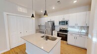 Located at 2700 Emerald Green Way in Knoxville, TN, this well-appointed 2-bedroom, 2-bathroom single-floor residence offers a thoughtfully designed layout with modern finishes throughout. The open-concept kitchen and living area serves as the heart of the home, anchored by a central island with a stainless steel sink and light quartz countertops. The kitchen is outfitted with crisp white cabinetry, a white subway tile backsplash, stainless steel appliances including a refrigerator, electric range, and over-the-range microwave, plus a built-in desk nook for added functionality. Warm-toned hardwood-style flooring and stylish black pendant lighting complete the space. The primary bedroom features hardwood-style flooring, a ceiling fan, a door with outdoor views, and direct access to an en-suite bathroom. The en-suite offers a long white vanity, framed mirror, tub-shower combo, and hardwood-style flooring. The second bedroom is carpeted and benefits from natural light through a large window with outdoor views and includes a closet. The second bathroom mirrors the clean aesthetic with a tub-shower combo. Additional spaces include a hallway, laundry room, pantry, utility room, and multiple closets, ensuring ample storage throughout.