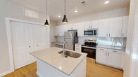 Located at 2700 Emerald Green Way in Knoxville, TN, this well-appointed 2-bedroom, 2-bathroom single-floor residence offers a thoughtfully designed layout with modern finishes throughout. The open-concept kitchen and living area serves as the heart of the home, anchored by a central island with a stainless steel sink and light quartz countertops. The kitchen is outfitted with crisp white cabinetry, a white subway tile backsplash, stainless steel appliances including a refrigerator, electric range, and over-the-range microwave, plus a built-in desk nook for added functionality. Warm-toned hardwood-style flooring and stylish black pendant lighting complete the space. The primary bedroom features hardwood-style flooring, a ceiling fan, a door with outdoor views, and direct access to an en-suite bathroom. The en-suite offers a long white vanity, framed mirror, tub-shower combo, and hardwood-style flooring. The second bedroom is carpeted and benefits from natural light through a large window with outdoor views and includes a closet. The second bathroom mirrors the clean aesthetic with a tub-shower combo. Additional spaces include a hallway, laundry room, pantry, utility room, and multiple closets, ensuring ample storage throughout.