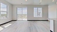 Unit 515 at 818 Melvin Ct is a contemporary 2-bedroom, 2-bathroom apartment offering 910 square feet of well-designed single-floor living space in Madison, WI. The unit features a clean modern aesthetic throughout, highlighted by light gray wood-style flooring and bold black trim accents that create a striking visual contrast against crisp white walls.

The spacious primary bedroom spans 590 square feet and opens to a private balcony through sliding glass doors, offering expansive outdoor views of the surrounding landscape. Natural light pours in through large windows, enhancing the airy, open feel. The second bedroom also benefits from generous natural light via a large window with scenic views and includes a dark-paneled sliding closet door that complements the unit's modern design language.

The kitchen is appointed with pendant lighting and features a clean, functional layout visible from the main living area. Both bathrooms are finished with large-format stone tile flooring, gray cabinetry with modern hardware, white countertops, and illuminated vanity mirrors. One bathroom includes a soaking tub and shower combination. The unit's consistent use of dark door frames and hardware throughout ties the contemporary design together cohesively, creating a polished, move-in-ready living environment.