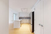 Located at 605 Concord Ave in Cambridge, MA, this well-designed one-bedroom, one-bathroom residence offers a thoughtful layout across a single floor. Light-toned hardwood flooring runs throughout, lending warmth and continuity to each space.

The open-concept kitchen and living area serves as the heart of the home. The kitchen is outfitted with sleek white cabinetry extending to the ceiling, a gray tile backsplash, stainless steel appliances including a gas range, microwave, and refrigerator, and a central island with a white countertop and undermount sink. Track lighting overhead provides focused illumination throughout the space. The adjoining living area is bright and open, with large floor-to-ceiling windows and a glass door leading to an outdoor balcony, framing lush, green tree views.

The bedroom is a calm and comfortable retreat, featuring a generous window overlooking the same verdant scenery, with ample natural light filling the room. Four closets throughout the unit offer exceptional storage capacity.

The bathroom is finished with large-format gray slate-style floor tiles, a full soaking tub with a tiled surround, and clean white fixtures. A dedicated laundry area and hallway complete the functional layout of this modern Cambridge residence.