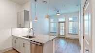Located at 112 Hera Way in Myrtle Beach, SC, this one-bedroom, one-bathroom residence offers a thoughtfully designed layout with modern finishes throughout. The open-concept living and kitchen area is anchored by a peninsula island topped with granite countertops, complemented by gray shaker-style cabinetry, a subway tile backsplash, and a full suite of stainless steel appliances including a refrigerator, dishwasher, microwave, and range. Pendant lighting hangs above the island, while high ceilings and a ceiling fan enhance the sense of openness. Light-toned hardwood-style flooring flows throughout the main living areas, and large windows with transom accents welcome generous natural light and exterior views. The bedroom is a comfortable, carpeted retreat featuring a ceiling fan, oversized windows with views of the surrounding neighborhood, and access to a well-appointed walk-in closet with built-in wire shelving and hanging rods. The bathroom offers a granite-topped vanity with gray cabinetry, brushed nickel fixtures, a large mirror, and a full tub and shower combination finished with classic white subway tile. Clean white walls and a consistent, contemporary design palette give the entire space a bright, cohesive ambiance.