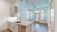 Located at 112 Hera Way in Myrtle Beach, SC, this one-bedroom, one-bathroom residence offers a thoughtfully designed layout with modern finishes throughout. The open-concept living and kitchen area is anchored by a peninsula island topped with granite countertops, complemented by gray shaker-style cabinetry, a subway tile backsplash, and a full suite of stainless steel appliances including a refrigerator, dishwasher, microwave, and range. Pendant lighting hangs above the island, while high ceilings and a ceiling fan enhance the sense of openness. Light-toned hardwood-style flooring flows throughout the main living areas, and large windows with transom accents welcome generous natural light and exterior views. The bedroom is a comfortable, carpeted retreat featuring a ceiling fan, oversized windows with views of the surrounding neighborhood, and access to a well-appointed walk-in closet with built-in wire shelving and hanging rods. The bathroom offers a granite-topped vanity with gray cabinetry, brushed nickel fixtures, a large mirror, and a full tub and shower combination finished with classic white subway tile. Clean white walls and a consistent, contemporary design palette give the entire space a bright, cohesive ambiance.