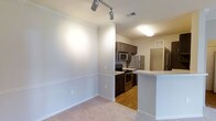Located at 1431 W Nine Mile Rd in Pensacola, Florida, this single-floor residence offers a well-designed, open-concept layout that maximizes both functionality and comfort. The living area features plush carpeting, crown molding, and adjustable track lighting, creating a bright and welcoming atmosphere. A half-wall peninsula connects the living space to the kitchen, providing a natural flow between the two areas while maintaining a sense of openness. The kitchen is thoughtfully appointed with rich, dark cabinetry, a full suite of stainless steel appliances including a refrigerator, microwave, and electric range, and durable hardwood-style flooring. Ample cabinet storage and generous counter space make the kitchen both practical and visually appealing. Neutral wall tones and consistent trim work throughout the space contribute to a clean, cohesive aesthetic. Ceiling-mounted lighting fixtures ensure each area is well-lit, and multiple HVAC vents indicate a comprehensive climate control system. The overall design balances modern finishes with a comfortable, livable feel, making this a functional and attractive single-level home in the heart of Pensacola.