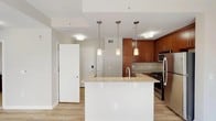 This one-bedroom, one-bathroom unit at 101 Washington Blvd in Stamford, CT offers a well-designed, single-floor layout with modern finishes throughout. The open-concept kitchen is a standout feature, showcasing rich warm-toned cabinetry, granite countertops, and a full suite of stainless steel appliances including a gas range, microwave, refrigerator, and dishwasher. A center island with a built-in sink and pendant lighting above provides both additional prep space and a casual dining area. Light hardwood-style flooring runs throughout the main living areas, creating a bright and cohesive feel. The bedroom is carpeted for comfort and benefits from dual windows that invite natural light and offer views of the surrounding area. The full bathroom is finished with tile flooring, a combined tub and shower with sliding glass doors, a wood vanity with a white countertop, and a large mirror framed by contemporary lighting fixtures. The unit's neutral color palette and clean architectural lines contribute to a polished, move-in-ready ambiance suited for comfortable urban living in downtown Stamford.