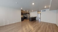 Located at 3957 S 300 E in Salt Lake City, Utah, this single-floor unit offers a thoughtfully designed, open-concept layout that maximizes both functionality and comfort. The living area is bright and spacious, featuring light hardwood-style flooring, recessed lighting, and large windows dressed with blinds that allow generous natural light to fill the space. A dedicated entry area with a front door and adjacent window adds a welcoming sense of arrival.

The kitchen is a standout feature, outfitted with dark espresso cabinetry, light granite countertops, and a full suite of stainless steel appliances, including a refrigerator, electric range with microwave above, and a kitchen island with additional counter space and storage. The seamless flow between the kitchen and living areas makes it ideal for both daily living and entertaining.

The bedrooms are carpeted for comfort and include large sliding or full-length windows with vertical blinds, providing outdoor views and natural light. The bathrooms are finished with matching dark cabinetry, granite vanity tops, hardwood-style tile flooring, and include a glass-enclosed walk-in shower in the primary bath and a half bath with a clean, minimalist design. The overall aesthetic throughout is modern and cohesive, with neutral tones and quality finishes.