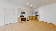 This well-designed one-bedroom, one-bathroom unit in Richmond, VA offers a thoughtfully laid-out single-floor plan that maximizes functionality and comfort. Light wood-tone luxury vinyl plank flooring flows consistently throughout the space, creating a warm and cohesive look from room to room.

The open-concept kitchen and living area serves as the heart of the unit. The kitchen is outfitted with a full suite of stainless steel appliances — including a refrigerator, range, microwave, and dishwasher — complemented by two-tone cabinetry featuring warm wood lower cabinets and crisp white upper cabinets with matte black hardware. A white tile backsplash and light quartz countertops complete the clean, modern aesthetic. Recessed lighting illuminates the space effectively.

The living area is bright and airy, benefiting from two large windows fitted with horizontal blinds that allow natural light to filter in while offering views of the surrounding Richmond streetscape. The bedroom is a comfortable, well-proportioned space that also features a pair of windows, a dedicated closet, and light-filled interiors.

The bathroom is finished with large-format cream floor tiles, a wood-toned vanity with a white countertop and integrated sink, a wall-mounted mirror, and a full tub-shower combination with clean white tile surround.