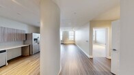 Located in the heart of downtown Rochester, this well-appointed one-bedroom, one-bathroom residence offers a thoughtfully designed single-floor layout with modern finishes throughout. The open-concept kitchen and living area serves as the central hub of the home, featuring wood-grain cabinetry, white quartz countertops, a subway tile backsplash, and a full suite of stainless steel appliances including a double wall oven, dishwasher, and French door refrigerator. Track lighting and warm hardwood-style flooring further elevate the space. A distinctive curved architectural column adds a unique design element to this area. The generously sized bedroom is finished with plush carpeting, track lighting, and large windows that frame sweeping views of the Rochester skyline, filling the room with natural light. The living area also benefits from dual windows offering the same urban vistas. The bathroom is outfitted with large-format tile flooring, a floating wood-toned vanity, a framed mirror, and a glass-enclosed shower. A dedicated in-unit laundry area houses a side-by-side Electrolux washer and dryer, adding everyday convenience. A closet completes the layout, offering practical storage in this polished urban residence.