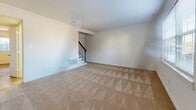 Located at 66 Lakeshore Dr in Hampton, Virginia, this two-story home offers a practical and well-organized layout across both levels. The main floor features a kitchen equipped with warm-toned wood cabinetry, dark countertops, stainless steel appliances including a range, microwave, and refrigerator, and a peninsula that provides additional prep and seating space. Tile flooring runs throughout the kitchen, and a ceiling fan with a door providing exterior access adds to the room's functionality. A stacked washer and dryer unit is conveniently housed in a dedicated laundry area on this level. A half bathroom with tile flooring, a wood vanity, and a angled ceiling detail is also found on the main floor.

The upper level features carpeted rooms filled with natural light from large windows with exterior views of surrounding greenery. A generously sized bedroom includes multiple closets with built-in rods, offering ample storage. A full bathroom on this level is outfitted with tile flooring and a full tub-shower combination. A staircase with dark wood balusters connects the two floors, contributing to the home's overall cohesive and clean aesthetic throughout.