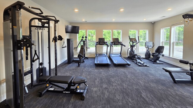 Un gimnasio espacioso con una variedad de equipos que incluyen cintas de correr, bicicleta estática, pesas y bancos, ubicado en la casa club de los apartamentos Greenwood Commons en Delaware, Ohio. - Greenwood Commons Apartments