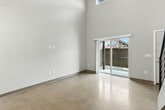 Located on W Broadway St in Missoula, Montana, this two-bedroom, two-bathroom loft-style residence spans two floors and delivers a striking industrial-modern aesthetic. The main floor opens into a spacious living area with polished concrete floors and soaring ceilings that amplify the sense of volume and light. The open-concept kitchen features a granite-topped peninsula, dark wood cabinetry, stainless steel appliances, and pendant lighting, with an exposed spiral ductwork detail that nods to the building's industrial character. A wood-and-steel staircase with a sleek horizontal-rail balustrade connects to the upper loft level, which features wood-look flooring, an exposed wood-beam ceiling structure, and an open railing overlooking the main floor below. The primary bedroom is generously proportioned with plush carpeting, vaulted ceiling height, and large windows that invite natural light and outdoor views. Both bathrooms are finished consistently with dark vanity cabinetry, granite countertops, and walk-in showers. Additional conveniences include dedicated closets, in-unit laundry, two patios, and hallway access between rooms. The space combines raw architectural details with refined finishes throughout.