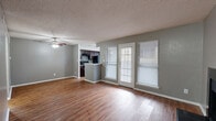 This single-story, 1-bedroom, 2-bathroom residence offers a practical and comfortable layout designed to maximize every square foot of its compact footprint. The open-concept main living area seamlessly integrates the living room, dining room, and kitchen into one cohesive space. Warm hardwood-style flooring extends throughout, complemented by neutral gray walls and a textured ceiling. A ceiling fan provides additional airflow, while a set of glass doors and flanking windows allow natural light to fill the living area. A standout feature is the black-tiled fireplace, which anchors one wall of the living space and adds a distinctive focal point.

The galley-style kitchen is well-equipped with rich dark cabinetry, granite countertops, a tile backsplash, and black appliances, including an electric range and full-sized refrigerator. A window above the sink brings in natural light.

The bedroom is a well-sized, quiet retreat with the same hardwood-style flooring and ample wall space. The unit includes two bathrooms, one of which features marble-style tiled walls surrounding a bathtub and a window for natural ventilation. Additional conveniences include two closets, a hallway, and an in-unit laundry area.