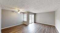 Located at 3099 Kirklevington Drive in Lexington, Kentucky, this 2-bedroom, 1-bathroom unit offers a practical and comfortable single-floor layout. The living area is highlighted by warm hardwood-style flooring, neutral gray walls, a textured ceiling, and a ceiling fan. Natural light fills the space through a side window and a sliding glass door that opens to a private balcony, providing outdoor access and views of the surrounding area. The galley-style kitchen is well-appointed with warm wood cabinetry, dark granite-style countertops, a double stainless steel sink, an electric range, a built-in microwave, a dishwasher, and a refrigerator, all set over easy-care hard flooring. The generously sized primary bedroom features plush carpeting and ample room to furnish comfortably. The second bedroom also offers carpeted flooring and a sliding closet with a built-in hanging rod for storage. Both bedrooms are finished with the same neutral tones found throughout the unit. The full bathroom includes a tub-shower combo with white tile surround, a vanity with a light countertop, and hardwood-style flooring. Consistent neutral tones and clean finishes throughout create a cohesive and move-in-ready living environment.