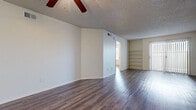 This single-story home offers three bedrooms and two bathrooms within a efficiently arranged floor plan. Throughout the home, wood-style laminate flooring provides a cohesive and low-maintenance foundation, complemented by textured ceilings and neutral white walls that create a clean, versatile backdrop.

The combined living and kitchen area forms the central hub of the home. The living room is generously proportioned, featuring a ceiling fan and open sightlines that connect directly to the kitchen. Built-in shelving along one wall adds functional storage and display space. The kitchen is designed for practicality, offering white cabinetry, speckled laminate countertops, a peninsula with a sink, and white appliances including an electric range with over-the-range microwave, dishwasher, and refrigerator.

The bedrooms each include ceiling fans and wood-style flooring. The primary bedroom is the largest of the three, providing comfortable living space. Two closets serve the home, including a walk-in closet equipped with multiple shelving units and hanging rods for organized storage.

The two bathrooms share a consistent design, featuring vanities with speckled countertops, white cabinetry, large mirrors, and tub-shower combinations. A hallway connects the various rooms, ensuring a logical and functional flow throughout the home.