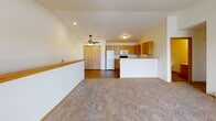 This single-floor residence offers a practical and comfortable layout designed for everyday living. The open-concept living and dining area is generously sized, featuring plush neutral carpeting, vaulted ceilings, a ceiling fan, and a built-in ledge shelf that adds a subtle architectural detail. Natural light filters in through vertical-blind-covered windows, and a baseboard heating system runs along the exterior walls throughout the space.

The kitchen is efficiently arranged with warm oak cabinetry providing ample storage, a double sink, laminate countertops, and a full suite of white appliances including a refrigerator, electric range, and microwave. A peninsula counter separates the kitchen from the living area, creating a natural flow between the two spaces.

The bedrooms are carpeted and bright, each featuring sliding closet doors and windows with views of the surrounding neighborhood. Baseboard heaters ensure consistent warmth in each room.

The bathroom is well-appointed with wood-look vinyl flooring, a full soaking tub and shower combination, a toilet, and a vanity with oak cabinetry and a large mirror with overhead lighting. Adjacent to the bathroom is a utility closet housing the water heater alongside additional shelving and hanging storage, maximizing the functional use of space throughout this well-organized unit.