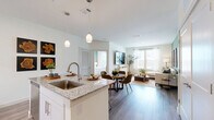 Located at 5600 Dancy Rd in Houston, TX, this well-appointed 2-bedroom, 2-bathroom single-story residence offers a thoughtfully designed open-concept layout. The combined kitchen and living area serves as the heart of the home, where a modern kitchen impresses with white shaker cabinetry, granite countertops, a subway tile backsplash, stainless steel appliances including a French door refrigerator, and a central island with pendant lighting and bar seating. The living room features wood-look flooring, a sage green accent wall, and large windows that welcome an abundance of natural light. Both bedrooms are generously proportioned, each equipped with ceiling fans, large windows, and dedicated walk-in closets outfitted with multi-level shelving and hanging rods. The primary bedroom is notably spacious and enjoys its own private en-suite bathroom. Both bathrooms are finished with granite-topped white vanities, framed mirrors, and wood-look flooring, with the primary bath also offering a glass-enclosed walk-in shower. A welcoming entrance, a connecting hallway, and two walk-in closets round out the floor plan, delivering a well-organized and comfortable living experience throughout.