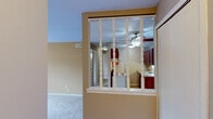Located at 7055 Round Hill Dr in Waterford, MI, this 2-bedroom, 2-bathroom residence offers a practical and comfortable single-floor layout. The galley-style kitchen is efficiently designed with rich dark wood cabinetry lining both walls, light countertops, a stainless steel sink, and standard appliances including a coil-top range and refrigerator, all finished with durable wood-look flooring. Adjacent to the kitchen, the combined living and dining area is carpeted and features warm neutral-toned walls, a ceiling fan with light fixture, and a sliding glass door that invites natural light and outdoor views. Both bedrooms are carpeted and painted in the same warm neutral palette, with vertical blinds providing window coverage. The primary bedroom offers a walk-in closet with built-in shelving, while the second bedroom features a set of bifold closet doors for convenient storage. The two bathrooms are similarly appointed, each with a rich wood vanity, light countertop, mosaic tile flooring, and brushed nickel fixtures. One bathroom includes a full tub-shower combination. A dedicated closet provides additional storage within the unit. The overall ambiance is clean, understated, and move-in ready.