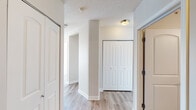 This single-floor unit is situated at a notable elevation within a high-rise building, offering expansive panoramic city views through large floor-to-ceiling windows that flood the living spaces with natural light. The open-concept living and dining area is finished with light wood-tone laminate flooring and neutral-toned walls, creating a bright and airy atmosphere complemented by textured ceilings throughout.

The kitchen is well-appointed with grey-toned cabinetry, dark granite countertops, and a full suite of stainless steel appliances, including a refrigerator, electric range, and over-the-range microwave. A pass-through counter connects the kitchen to the main living area, enhancing the open feel of the layout.

The hallway area features multiple closets with arched panel doors, providing ample built-in storage. A structural column adds an architectural element to the corridor space.

Two bathrooms serve the unit. The primary bathroom includes a standalone glass-door shower, a white vanity with a light countertop, and a wall-mounted mirror cabinet. The secondary bathroom features a white vanity with drawer storage, a large wall mirror, and updated lighting fixtures. Both bathrooms continue the light wood-tone flooring found throughout the unit, maintaining a cohesive aesthetic.