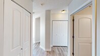 This single-floor unit is situated at a notable elevation within a high-rise building, offering expansive panoramic city views through large floor-to-ceiling windows that flood the living spaces with natural light. The open-concept living and dining area is finished with light wood-tone laminate flooring and neutral-toned walls, creating a bright and airy atmosphere complemented by textured ceilings throughout.

The kitchen is well-appointed with grey-toned cabinetry, dark granite countertops, and a full suite of stainless steel appliances, including a refrigerator, electric range, and over-the-range microwave. A pass-through counter connects the kitchen to the main living area, enhancing the open feel of the layout.

The hallway area features multiple closets with arched panel doors, providing ample built-in storage. A structural column adds an architectural element to the corridor space.

Two bathrooms serve the unit. The primary bathroom includes a standalone glass-door shower, a white vanity with a light countertop, and a wall-mounted mirror cabinet. The secondary bathroom features a white vanity with drawer storage, a large wall mirror, and updated lighting fixtures. Both bathrooms continue the light wood-tone flooring found throughout the unit, maintaining a cohesive aesthetic.