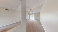 Located at 4711 S Himes Ave in Tampa, Florida, this 2-bedroom, 2-bathroom residence offers a functional and comfortable single-floor layout. The living room is a standout area, featuring vaulted ceilings, a ceiling fan with light fixture, and plush wall-to-wall carpeting. Large sliding glass doors with vertical blinds open to a private balcony, allowing natural light to fill the space. A pendant light marks the transition between the living area and the kitchen, which is connected via a pass-through counter with dark granite-style countertops. The kitchen is equipped with white cabinetry, black appliances including a refrigerator and dishwasher, a double sink beneath a window, and wood-look flooring. A conveniently located pantry closet provides additional storage. The two bedrooms are carpeted and bright, each with a ceiling fan and window. The primary bedroom benefits from a spacious walk-in closet outfitted with wire shelving systems for organized storage. Both bathrooms feature wood-look flooring, white vanity cabinetry, and a clean, neutral palette. A hallway connects the bedrooms and bathrooms, completing this well-organized and practical layout ideal for comfortable everyday living in South Tampa.
