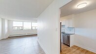 Located on the 15th floor at 25 Cougar Crt in Toronto's Scarborough neighbourhood, this well-appointed 2-bedroom, 1-bathroom unit offers a clean, modern aesthetic throughout. Light-toned hardwood flooring flows seamlessly across all living areas, complementing the crisp white walls and creating a bright, airy atmosphere.

The expansive living area is a standout feature, anchored by a wide bank of floor-to-ceiling windows that flood the space with natural light and frame sweeping views of the surrounding landscape. Baseboard heating runs along the window walls, ensuring year-round comfort.

The kitchen is thoughtfully designed with white shaker-style cabinetry, dark countertops, a classic subway tile backsplash, a stainless steel double sink, and stainless steel appliances including a French door refrigerator and dishwasher — offering both style and functionality.

The generously sized primary bedroom provides an abundance of space, with large windows offering outdoor views and built-in sliding closets delivering ample storage. The second bedroom is equally bright, featuring its own window with natural light and baseboard heating.

The bathroom is finished with elegant white subway tile surrounding a full soaker tub and shower, accented by polished chrome fixtures. The overall design of this unit is cohesive, modern, and move-in ready.