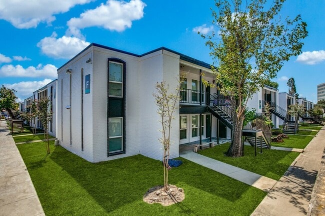 Arquitectura moderna rodeada de exuberantes jardines verdes y pasillos abiertos. - Palatia Apartment Homes