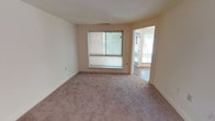 This single-floor residence offers a well-organized layout designed for comfortable everyday living. The bedrooms are generously proportioned, each featuring soft wall-to-wall carpeting, neutral wall tones, and windows fitted with horizontal blinds that allow for adjustable natural light. One bedroom stands out with a large walk-in closet equipped with built-in shelving, providing ample storage. Another bedroom benefits from a wide picture window framing views of lush greenery outside.

The galley-style kitchen is efficiently arranged with warm honey-toned wood cabinetry lining both sides, dark granite-style countertops, and hardwood-look flooring. White appliances, including a gas range and refrigerator, complement the clean aesthetic, while a pendant light overhead illuminates the passageway leading to the adjoining dining area.

The dining area is bright and open, anchored by a contemporary pendant light fixture and carpeted flooring, offering a comfortable gathering space. Two full bathrooms serve the unit, each featuring light-toned countertops, wood-toned cabinetry, a tub-shower combination with tile surround, a large vanity mirror, and Hollywood-style lighting. The overall ambiance throughout is clean, understated, and move-in ready.