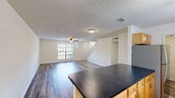 This well-designed townhome in Cambridge Woods offers a blend of comfort and functionality across two floors. The 1070 square feet of living space is thoughtfully distributed, with 550 sq ft on the ground floor and 520 sq ft upstairs. The home boasts 2 bedrooms, including a generous primary bedroom of 170 sq ft, and 3 bathrooms for added convenience.

The interior showcases a modern aesthetic with sleek vinyl plank flooring throughout, creating a cohesive look. The open-concept living area on the main floor is bathed in natural light from large windows, complemented by recessed lighting and ceiling fans for optimal comfort. A white staircase leads to the upper level, adding architectural interest to the space.

The updated kitchen features honey-toned wooden cabinets, contrasting dark countertops, and a stylish tile backsplash. Stainless steel appliances and track lighting complete the contemporary look. Bathrooms are equipped with modern fixtures, including a shower-tub combo with decorative tile accents.

Both bedrooms offer ample space and are equipped with ceiling fans for comfort. The home also includes two closets for storage. With its neutral color palette and modern amenities, this townhome provides a blank canvas for personalization while offering move-in ready convenience.