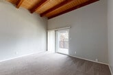 Located at 10025 E Girard Ave in Denver, CO, this one-bedroom, one-bathroom residence offers a thoughtfully laid-out single-floor plan with standout architectural character. The living room immediately impresses with soaring vaulted ceilings adorned with rich, exposed wood beams and tongue-and-groove wood paneling overhead, creating a warm and dramatic atmosphere. Soft carpeting runs throughout, and a sliding glass door opens to a private balcony, flooding the space with natural light and providing outdoor views. The kitchen is well-appointed with crisp white shaker cabinetry, marble-style countertops, wood-look vinyl flooring, and a full suite of black appliances including a gas range, dishwasher, and refrigerator — offering both style and functionality. The spacious primary bedroom is generously sized, featuring neutral carpet, a window for natural light, and access to a dedicated closet. The full bathroom includes a tub/shower combo and wood-look flooring, maintaining a clean, cohesive aesthetic throughout. Neutral gray tones across all rooms lend the space a modern, move-in-ready feel, while the vaulted ceiling design sets this residence apart with a sense of openness and volume rarely found in similarly sized homes.