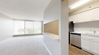 Located at 1417 Valley Lake Dr in Schaumburg, IL, this well-appointed 2-bedroom, 2-bathroom residence offers a thoughtfully designed single-floor layout. The combined kitchen and living area forms the heart of the home, where the kitchen stands out with white shaker-style cabinetry, stainless steel appliances including a refrigerator and dishwasher, white countertops, and wood-look plank flooring. A half-wall pass-through connects the kitchen to the living room, creating an open, communicative feel between the spaces. The spacious living room features plush carpeting, vertical blinds, and a large floor-to-ceiling window that invites abundant natural light and outdoor views. Both bedrooms are carpeted and neutral in tone, with the primary bedroom offering generous proportions, a wall-mounted AC unit, and access to a closet. The second bedroom is similarly well-sized and bright. Both bathrooms are clean and functional, with the full bath featuring wood-look tile flooring, white subway tile surrounding a tub-shower combo, and crisp white fixtures. A hallway with two closets provides practical storage. Baseboard heating is present throughout, ensuring year-round comfort. The overall aesthetic is clean, neutral, and move-in ready.