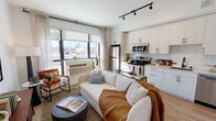 Located at 2501 38th Ave NE in St. Anthony, Minnesota, this single-floor unit offers a thoughtfully designed open-concept layout that seamlessly connects the living, dining, and kitchen areas. Large floor-to-ceiling windows flood the living space with natural light and provide views of the surrounding neighborhood, creating an airy, welcoming atmosphere. Track lighting overhead adds a modern, functional touch throughout.

The kitchen is well-appointed with white cabinetry featuring black hardware, a subway tile backsplash, stainless steel appliances including a refrigerator, electric range, microwave, and dishwasher, along with ample counter and storage space. Light wood-tone flooring runs consistently throughout the unit, enhancing the cohesive, contemporary aesthetic.

The bedroom is a calm retreat with a ceiling fan, a spacious sliding-door closet, and soft neutral tones. The bathroom is clean and modern, featuring white walls, light wood flooring, a full soaking tub with a shower, matte black fixtures, and a floating vanity with generous storage. Overall, the unit presents a sleek, functional design with a warm and inviting ambiance.