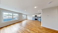 Located at 111 E Seneca St in Manlius, NY, this well-appointed one-bedroom, one-bathroom unit offers a thoughtfully designed single-floor layout. Warm-toned hardwood flooring flows consistently throughout every room, creating a cohesive and inviting atmosphere.

The open kitchen and living area serves as the heart of the unit. The kitchen features two-tone cabinetry — white upper cabinets paired with soft blue lower cabinets — complemented by a blue-and-white mosaic tile backsplash and a full suite of stainless steel appliances, including a refrigerator, range, microwave, and dishwasher. The spacious living room benefits from large windows that invite abundant natural light and offer views of the surrounding neighborhood.

The bedroom is a comfortable, well-sized room equipped with a ceiling fan, recessed lighting, and a generous double-door closet. Natural light enters through a window with neighborhood views, adding to the room's airy feel.

The full bathroom is clean and modern, featuring hardwood flooring, a white vanity with a large mirror, and a walk-in shower with elegant marble-style tile surround and glass sliding doors. A utility room provides additional functional space. Recessed lighting throughout enhances the unit's clean, contemporary aesthetic.