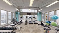The Whitney's fitness center is a generously sized, single-floor facility designed to support a comprehensive workout experience. The space is defined by soaring ceilings with an exposed industrial-style roof structure, lending it an open and airy feel. Large floor-to-ceiling windows and clerestory windows wrap around the perimeter, flooding the interior with abundant natural light and offering views of the surrounding outdoor pool area and landscaped grounds.

The flooring throughout consists of durable, neutral-toned carpet tiles arranged in a multi-directional pattern, providing both comfort and practicality underfoot. Vibrant teal accent walls punctuate the otherwise neutral gray color palette, adding energy and visual interest to the space.

The cardio zone is well-stocked with multiple treadmills, elliptical trainers, upright and recumbent bikes, and rowing machines — all from True Fitness. A wall-mounted flat-screen television is positioned for easy viewing during workouts. A dedicated free weights area features a full dumbbell rack, spin bikes, stability balls, resistance bands, and functional training accessories. A small refreshment counter and a water station are also present, adding convenience. A split-system HVAC unit ensures year-round comfort throughout the facility.