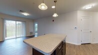 Located at 101 Pelican Dr in Groton, Connecticut, this single-floor residence offers a thoughtfully designed open-concept layout with modern finishes throughout. The kitchen serves as a central highlight, featuring dark espresso cabinetry, granite-style countertops, a center island with pendant lighting, and a full suite of stainless steel appliances including a refrigerator, range, and built-in microwave. Wood-style flooring flows through the main living and kitchen areas, adding warmth and continuity to the space. The living area is bathed in natural light through a large sliding glass door fitted with vertical blinds, opening to views of the surrounding greenery. Bedrooms are carpeted for comfort and include windows overlooking the outdoors, while a spacious walk-in closet with wire shelving provides ample storage. The bathrooms are finished with a classic black-and-white mosaic tile floor and dark vanity cabinetry with brushed nickel hardware. One bathroom includes a walk-in shower, while the other features a full tub-shower combination. Clean white walls and neutral tones throughout create a bright, versatile atmosphere ready for personalization.