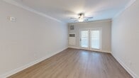 Located at 2700 Seabiscuit Lane in Greensboro, NC, this single-floor, 2-bedroom, 2-bathroom unit offers a thoughtfully designed layout across a comfortably sized floor plan. The open kitchen and living area serve as the heart of the home, where the kitchen stands out with floor-to-ceiling white shaker cabinetry, a subway tile backsplash, dark granite countertops, and a contrasting island topped with light granite and an undermount sink illuminated by pendant lighting. Black appliances and light hardwood-style flooring complete the polished look. The living room features crown molding, a ceiling fan, and French doors that invite natural light. Both bedrooms are carpeted and equipped with ceiling fans; the generously sized primary bedroom includes multiple windows with outdoor views and two walk-in closets outfitted with wire shelving systems. The two bathrooms are finished with granite-topped vanities, framed mirrors, and tub-shower combinations with curved curtain rods. A dedicated laundry room with wire shelving and hardwood-style flooring adds everyday convenience to this well-rounded home.