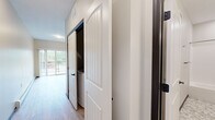 Located at 415 Hickory Dr in Cannon Falls, MN, this studio unit offers a thoughtfully designed single-floor layout that maximizes every square foot of living space. The open-concept kitchen and dining area serves as the heart of the unit, showcasing rich dark-toned cabinetry, granite-look countertops, and a full suite of stainless steel appliances including a refrigerator, range, and microwave. Pendant lighting above the kitchen peninsula adds a stylish, modern touch, while light hardwood-style flooring flows seamlessly throughout, brightening the space and creating a cohesive aesthetic. Natural light fills the area through well-placed windows and a sliding door that opens to a private balcony overlooking lush greenery — a standout feature that enhances the unit's connection to the outdoors. The hallway leads to a clean, well-finished full bathroom featuring a tub/shower combo with chrome fixtures, a granite-topped vanity with dark wood cabinetry, and penny-tile flooring that adds a refined detail. White panel doors with matte black hardware add a contemporary farmhouse touch throughout. The neutral color palette and clean lines give the space a fresh, modern ambiance that is both functional and inviting.